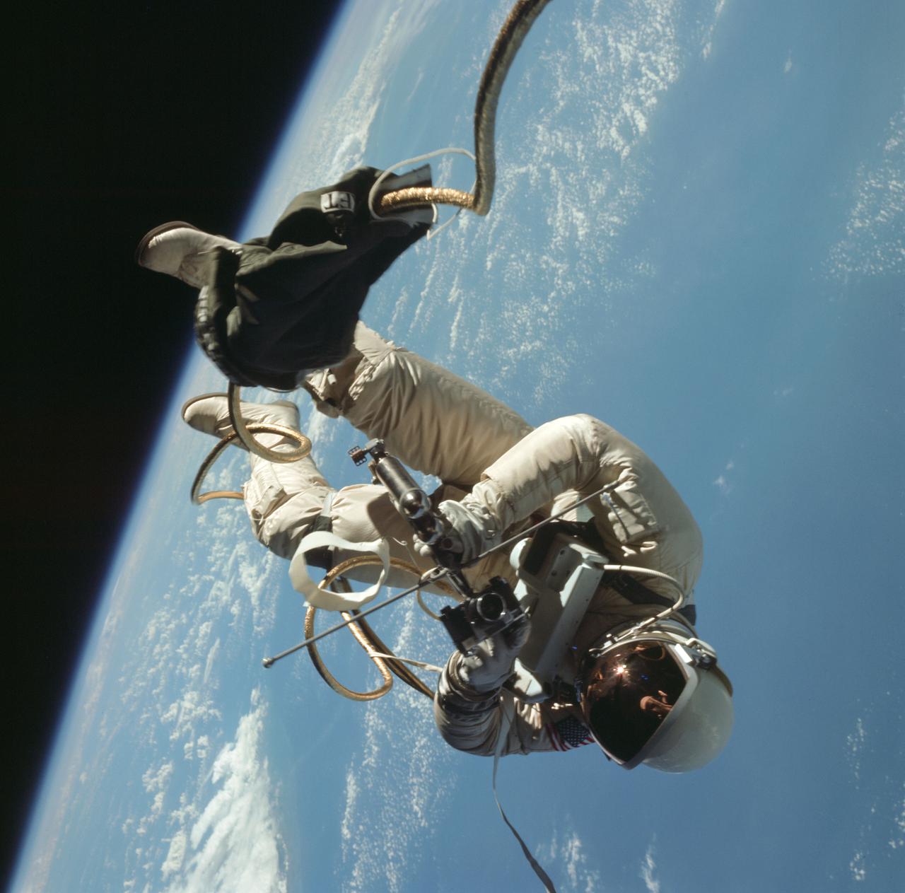 Astronaut Edward H. White II, pilot of the Gemini IV four-day Earth-orbital mission, floats in the zero gravity of space outside the Gemini IV spacecraft. White wears a specially designed spacesuit; and the visor of the helmet is gold plated to protect him against the unfiltered rays of the sun. He wears an emergency oxygen pack, also. He is secured to the spacecraft by a 25-feet umbilical line and a 23-feet tether line, both wrapped in gold tape to form one cord. In his right hand is a Hand-Held Self-Maneuvering Unit (HHSMU) with which he controls his movements in space.  Astronaut James A. McDivitt, command pilot of the mission, remained inside the spacecraft.    EDITOR'S NOTE: Astronaut White died in the Apollo/Saturn 204 fire at Cape Kennedy on Jan. 27, 1967.