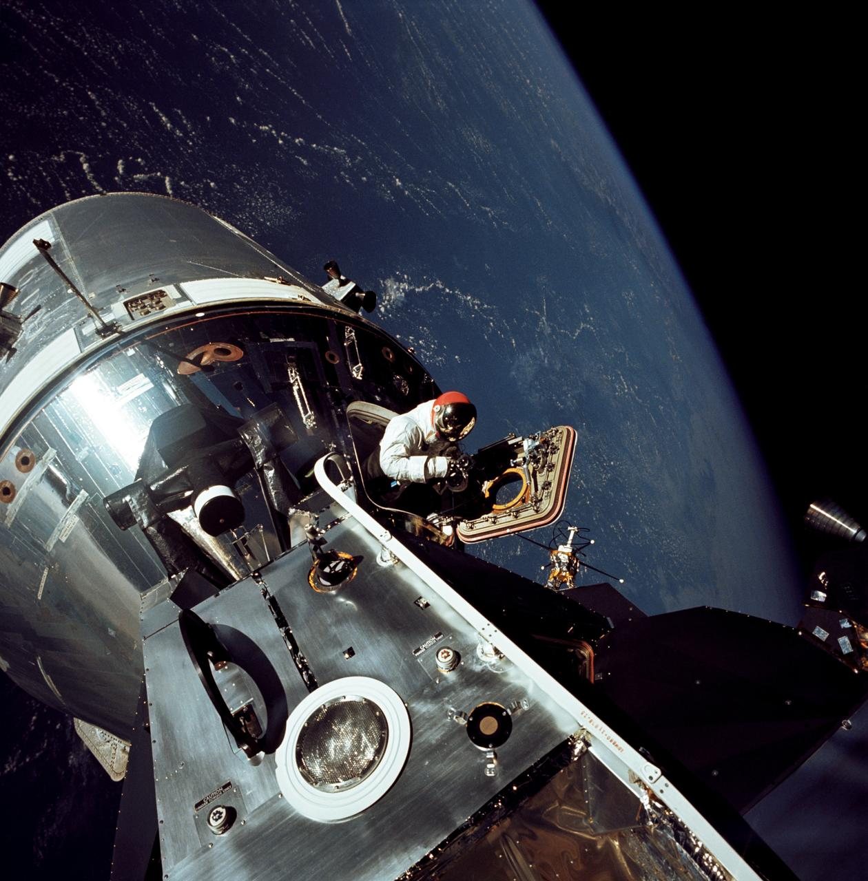 Apollo 9 in Earth orbit, March 1969: the command and service module docked with the lunar module, David Scott in the open hatch.