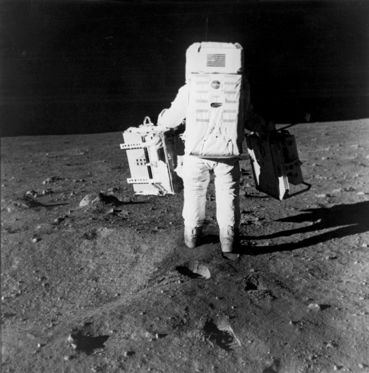 Buzz Aldrin carries the Apollo 11 seismometer and laser ranging retroreflector packages to their deployment site, 20 July 1969.