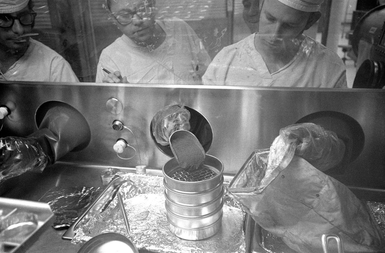 Glove handlers work with freshly opened Apollo 14 lunar sample material in modularized cabinets in the Lunar Receiving Laboratory at the Manned Spacecraft Center. The glove operator on the right starts to pour fine lunar material which he has just taken from a tote bag. The powdery sample was among the last to be revealed of the 90-odd pounds of material brought back to Earth by the Apollo 14 crew members.