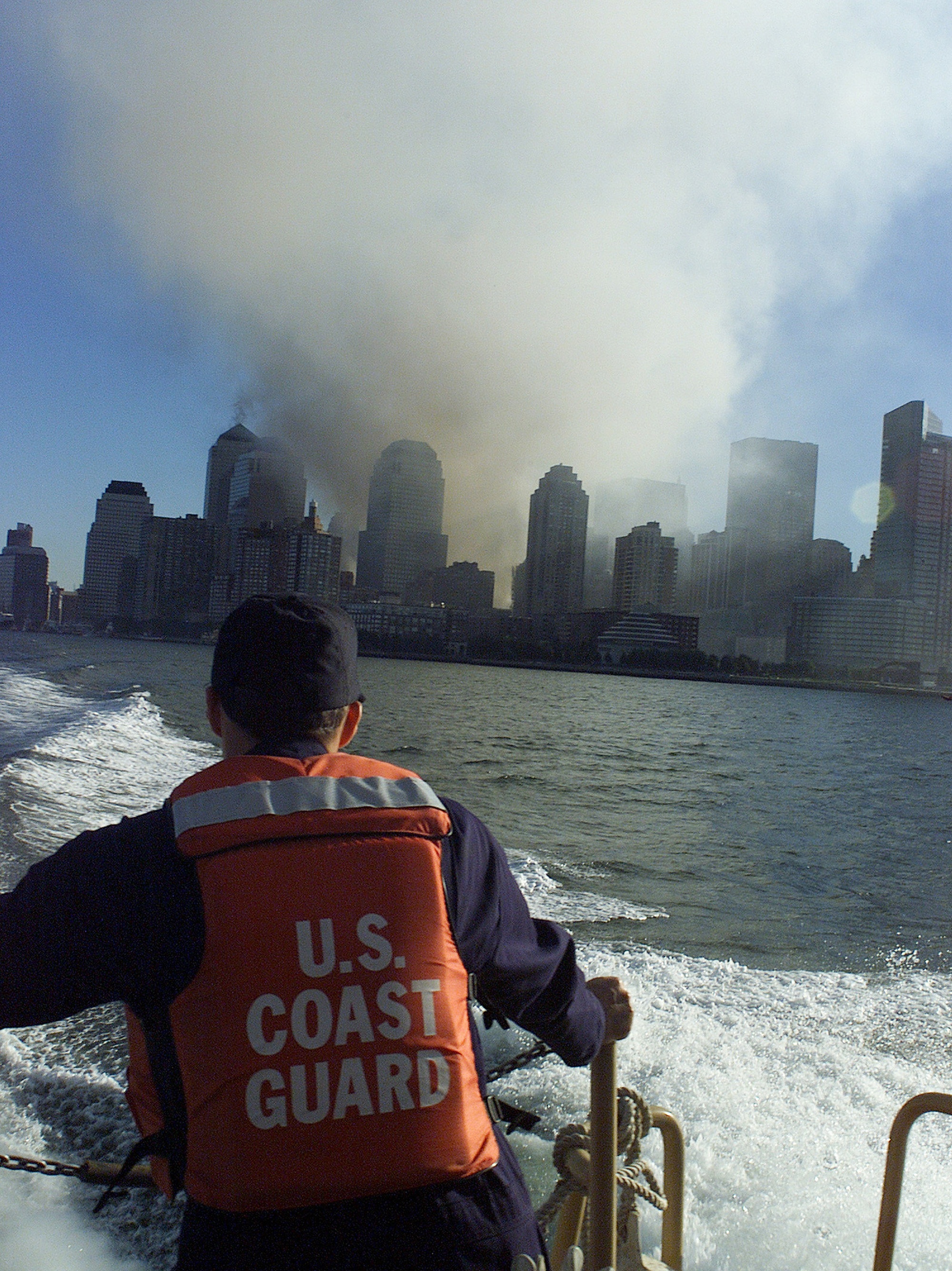 A Coast Guard patrol boat secures New York Harbor as smoke rises from the World Trade Center site, September 11, 2001.